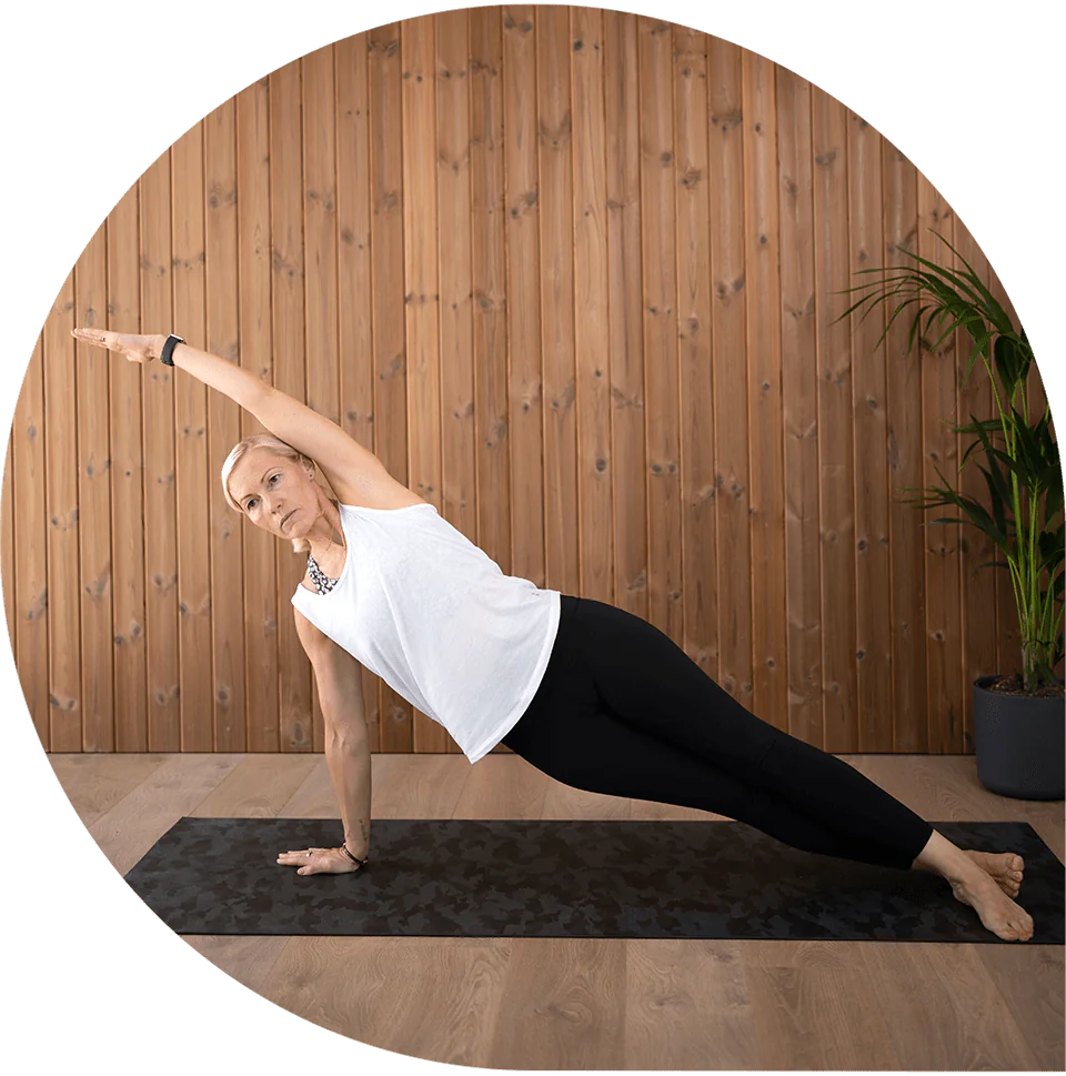 Lisa holding a side plank with one arm raised in the studio