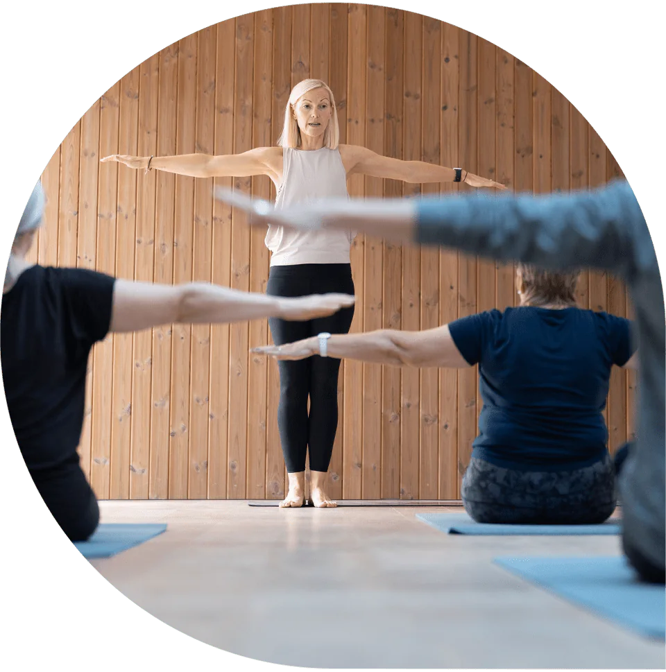 Lisa leading a class through an arm-raise exercise, seen from behind the group
