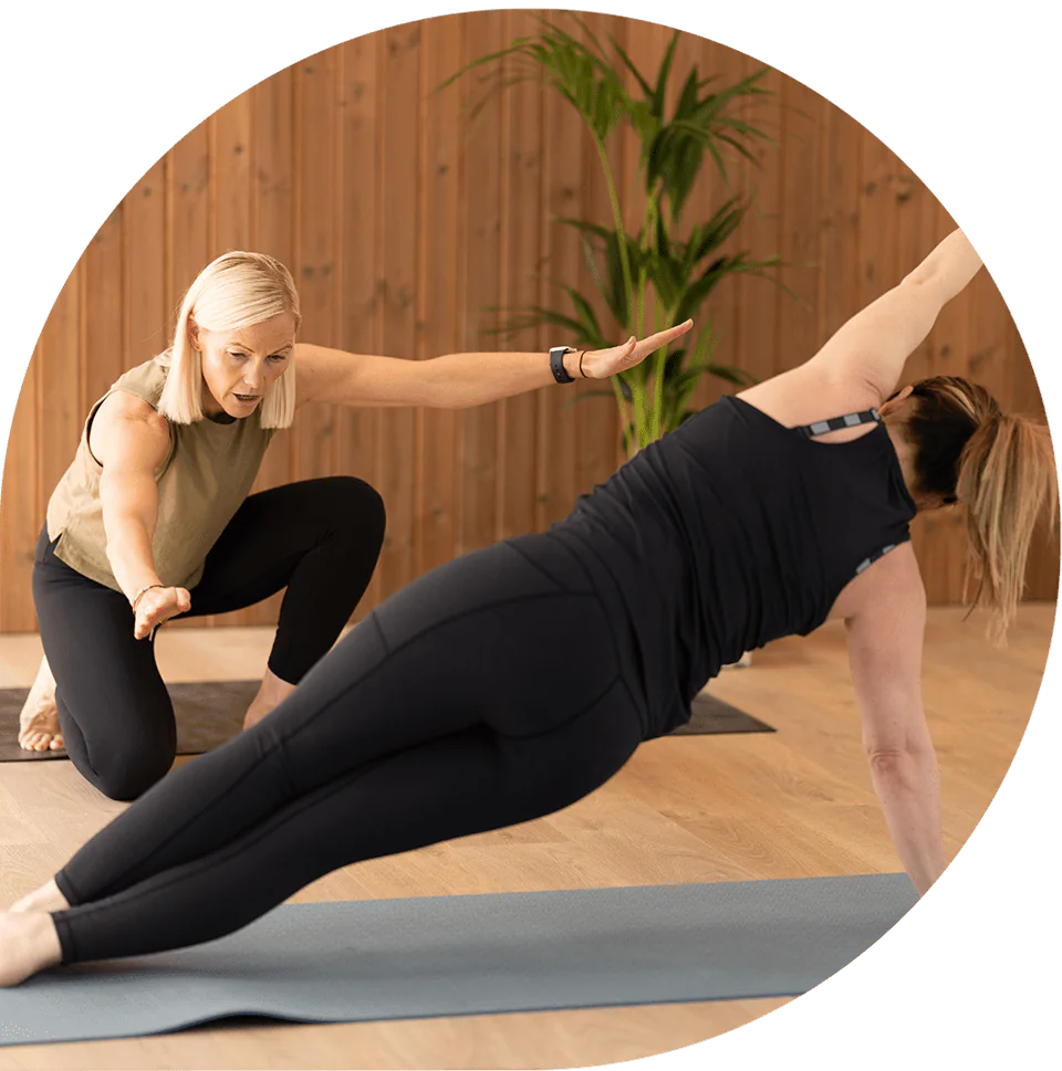 Lisa supporting a client holding a side plank with one arm raised