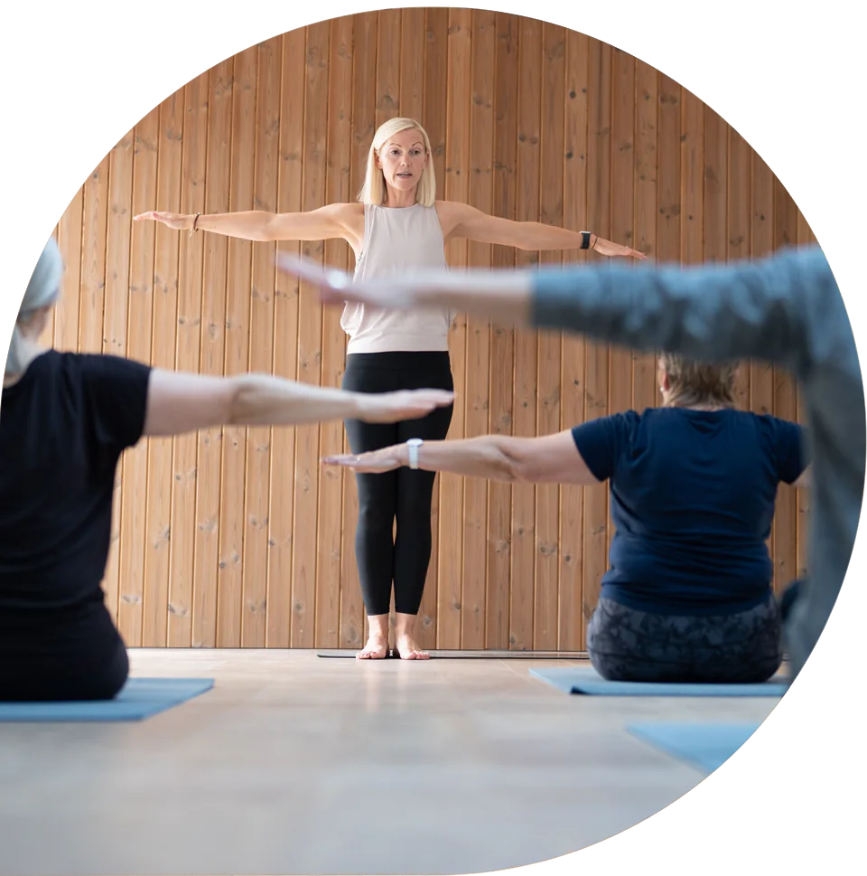 Lisa leading a group through an arms-out exercise in the studio
