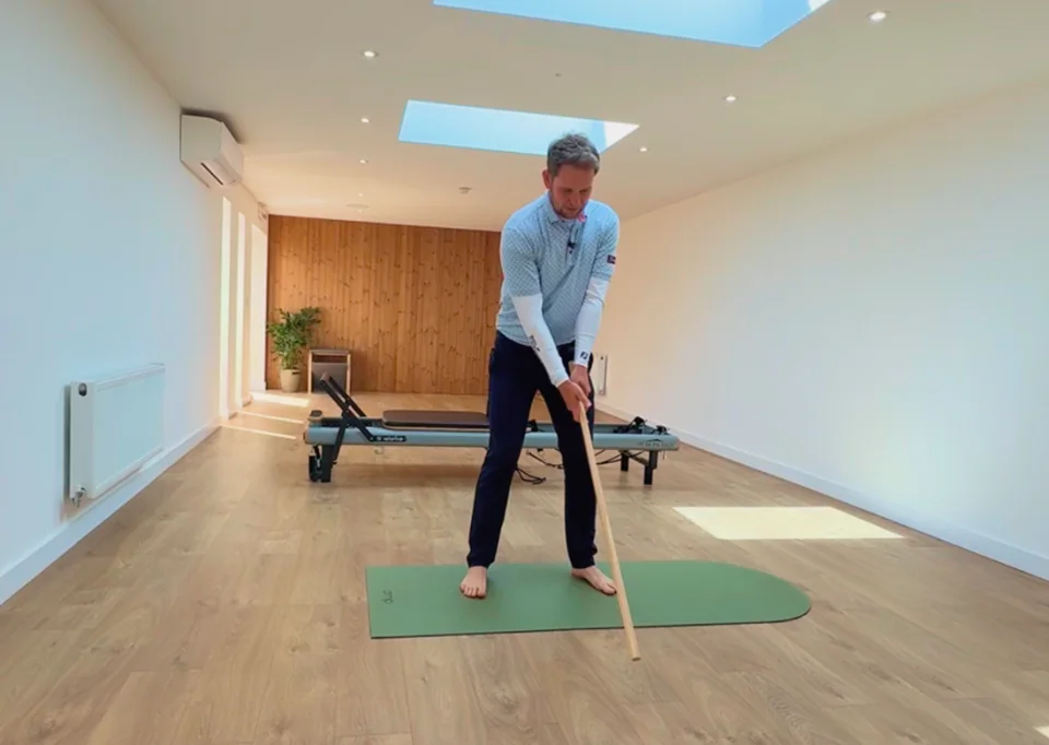 Pro golfer Adam Pike holding his swing position with an alignment stick